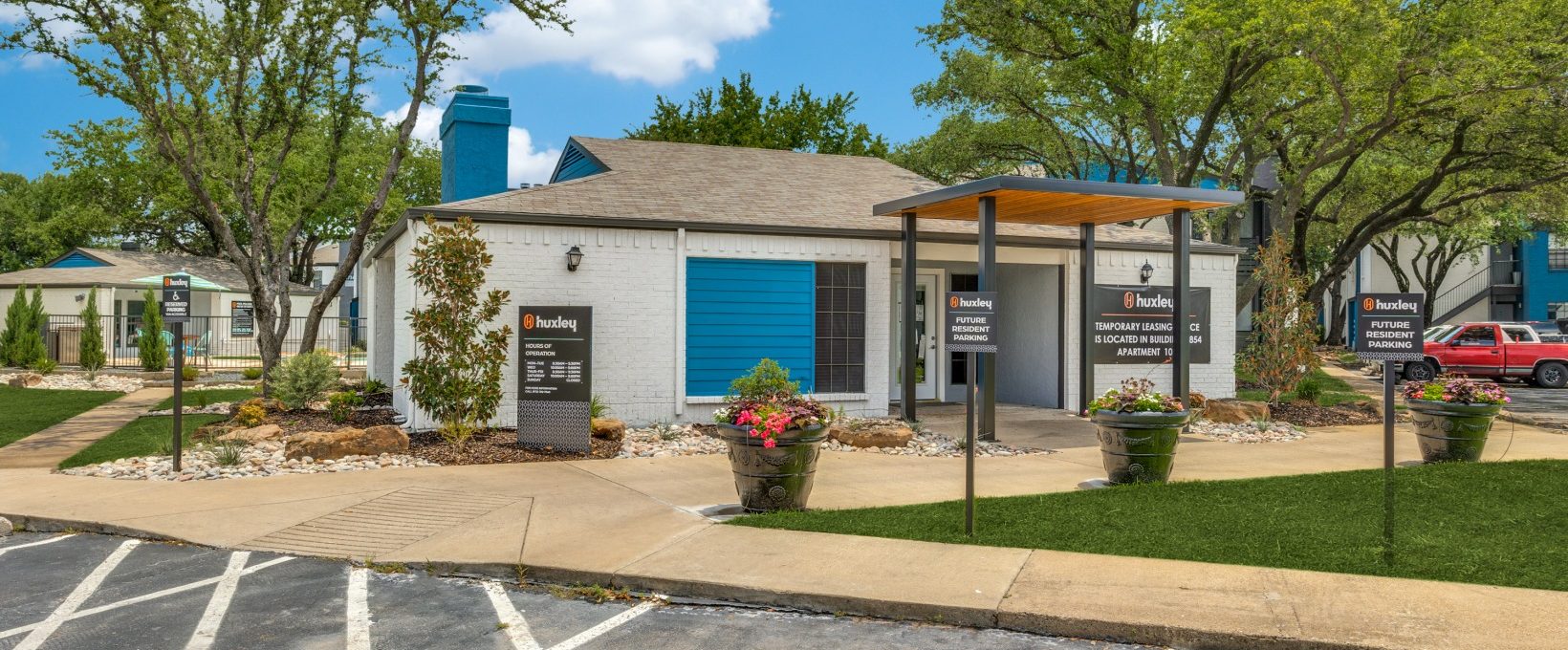 the exterior of a building with a parking lot and trees at The The Huxley