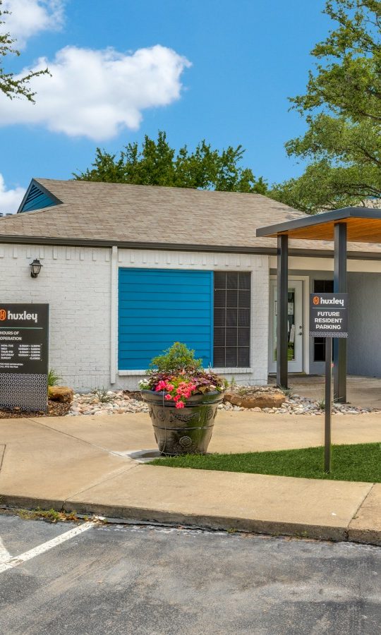 the exterior of a building with a parking lot and trees at The The Huxley