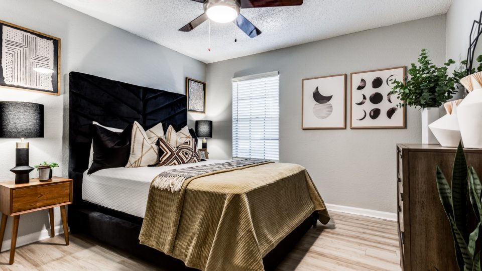 a bedroom with a black headboard and ceiling fan at The The Huxley